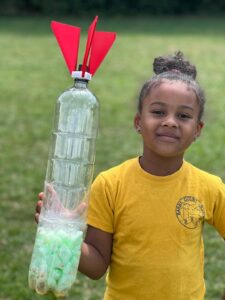 Outdoor learning activity - girl outside with rocket post launch